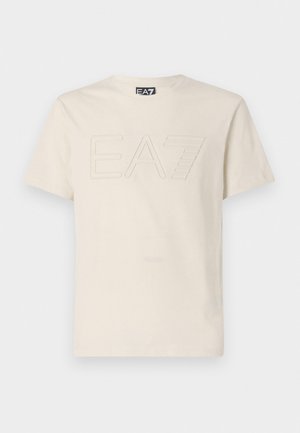 T-shirt in cotone color crema con maniche corte, caratterizzato da un logo "EA7" in rilievo sulla parte anteriore. Tessuto morbido e scollo rotondo classico.