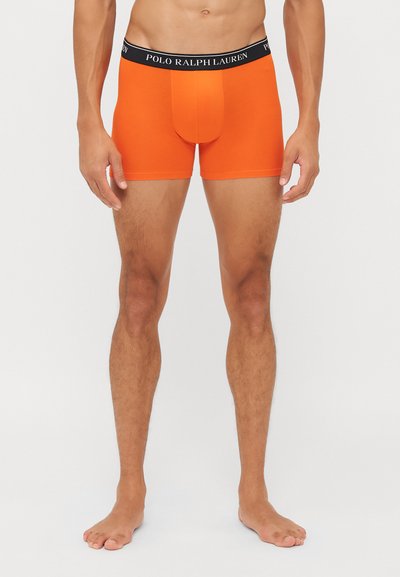 Oranžni bokserice z oprijetim dizajnom, ki imajo črn pas z marca "POLO RALPH LAUREN." Narejene iz gladkega, elastičnega materiala.