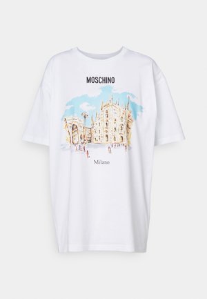 Valkoinen Moschino T-paita, jossa värikäs kuva Milano katedraalista ja sitä ympäröivistä rakennuksista sinisen taivaan alla.