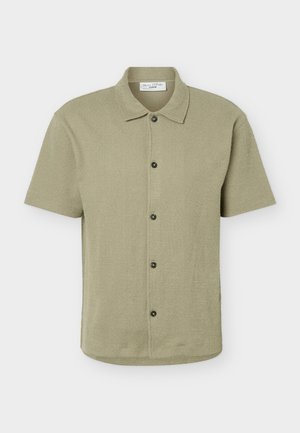 Kortærmet knappeskjorte i lyse olivengrøn med klassisk krave og fem mørke knapper foran.