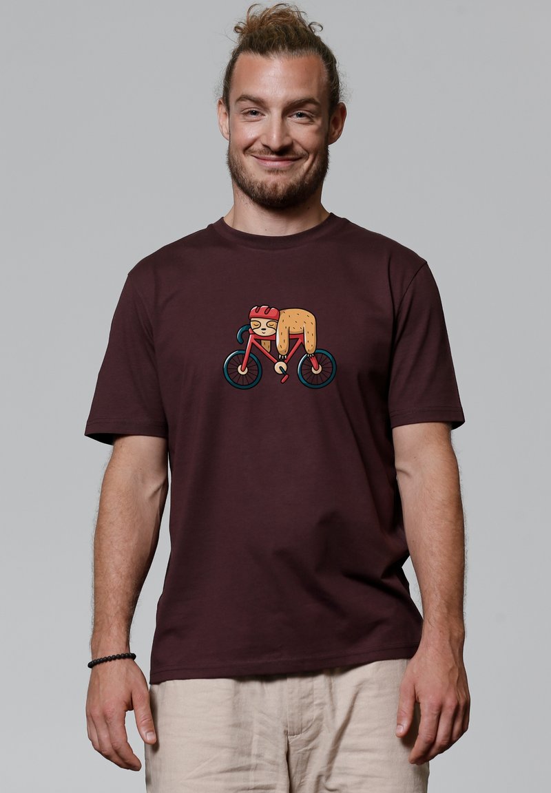 Bordeaux katoenen t-shirt met een kleurrijke bedrukte afbeelding van een personage op een fiets. Korte mouwen en een ontspannen pasvorm.
