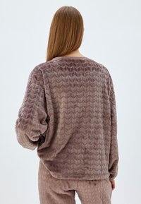 Rakennepintaista mauve fleece-paitaa, jossa on sepeeruskuvio, pyöreä pääntie ja rento istuvuus. Pehmeä, muhkeaa kangasta pitkillä hihoilla.