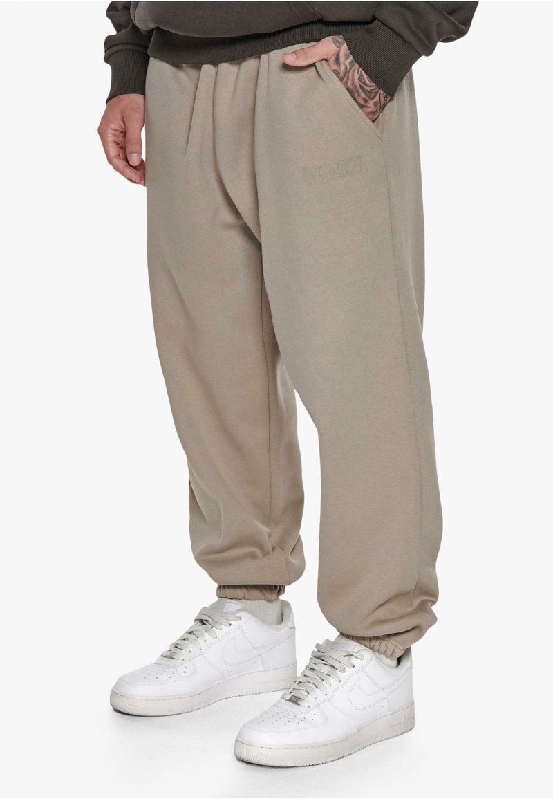 Beige broek met een relaxed fit, voorzien van zijzakken en geribbelde manchetten. Draagt u met witte sneakers, wat een eenvoudige, casual uitstraling geeft.