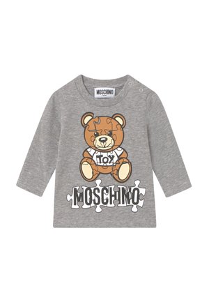Camisa de manga larga gris con un gráfico de un oso de dibujos animados que presenta detalles de piezas de rompecabezas. "Moschino" está impreso en letras negritas de color negro debajo del diseño.