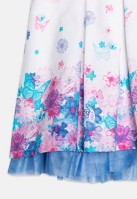 Tessuto bianco con motivi floreali e farfalle in rosa, blu e viola, sovrapposto a un orlo a volant in rete blu.