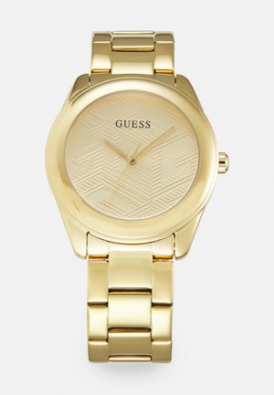 Orologio da polso dorato con quadrante testurizzato di colore oro che presenta motivi geometrici. Bracciale in metallo con maglie lisce e lucide. Nome del marchio in evidenza.