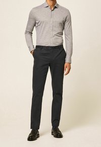 Jasnoszara koszula z guzikami, slim fit, teksturowany materiał; ciemnoniebieskie spodnie, zwężane; czarne loafersy; prosty, schludny design.