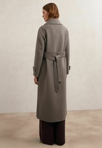 Lange grijze jas met een ceintuur in de taille, zijzakken en een reverskraag, gemaakt van een zachte wolmix met een gladde textuur.