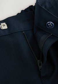 Hose aus marineblauem Stoff mit Knopfverschluss und verdeigten Reißverschluss. Das Material hat eine feine Textur mit leichtem Stretch und sorgfältigen Nähten.
