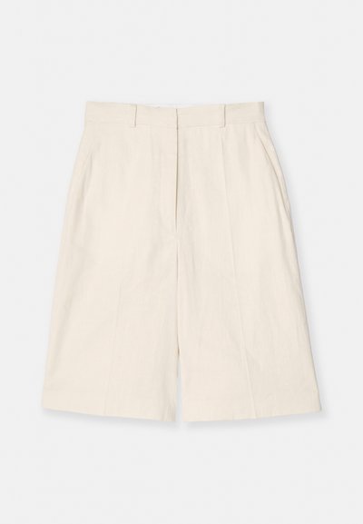 Shorts crème arrivant au genou avec des passants de ceinture, des poches latérales et un pli à l'avant sur fond blanc.