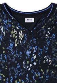 Blouse foncée à motifs avec des taches abstraites bleu, vert et blanc, col en V et col noir avec un détail de rayure bleue et étiquette de marque CECIL.