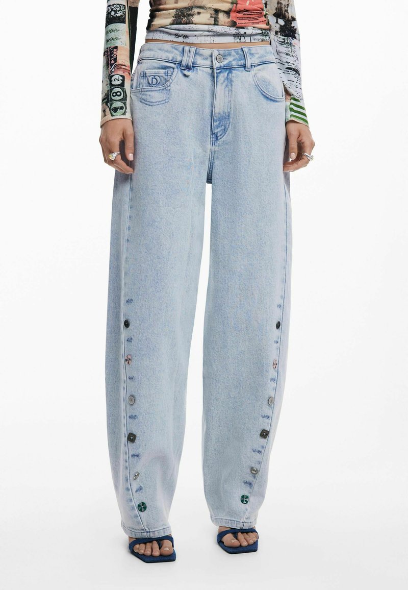 Hellblaue weite Jeans, mit einer geknöpften Seitennaht, die eine verblasste Denim-Textur und subtile Stickdetails aufweisen.