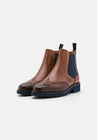 Bottines Chelsea en cuir marron avec un bout texturé, des panneaux latéraux élastiques et une semelle bleue contrastante. Présente des détails de brogue à l'avant.