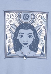 Blå t-shirt med en grafisk design av en kvinna med mörkt hår, halsband samt invecklade mönster av svängningar och geometriska former.