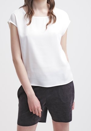 Hvid kortærmet top med rund halsudskæring, glat tekstur, kombineret med mørkegrå shorts med frontlommer og blød overflade.