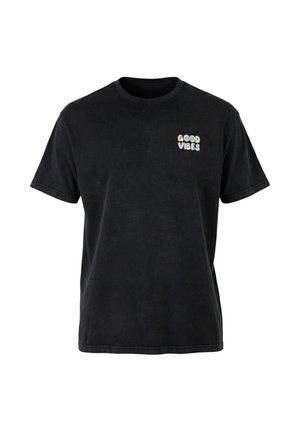 Svart t-skjorte med korte ermer og liten pastellfarget tekst "GOOD VIBES" på øvre venstre bryst i rundede bokstaver.