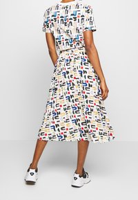 Ensemble à deux pièces imprimé, comprenant un haut à manches courtes et une jupe mi-longue. Les couleurs incluent le blanc, le noir, le bleu, le rouge et l'or.