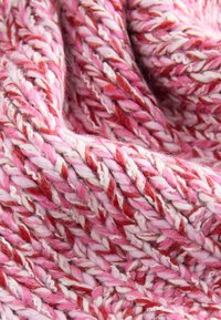 Tissu tricoté épais et doux avec un fil torsadé aux nuances de rose, blanc et rouge, montrant une texture détaillée et des fibres entrelacées.