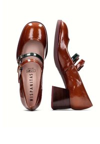 Chaussures Mary Jane en cuir verni marron avec un bout arrondi, deux brides décoratives et un talon épais et texturé. Marque : HispaniTas.