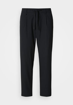 Schwarze, tapered Hosen mit elastischem Bund und Kordelzug, vorderen Falten und Seitentaschen auf weißem Hintergrund.