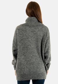 Pull gris surdimensionné avec un col tricoté haut, des manches longues et une texture douce ; présente un ourlet arrière plus long pour une couverture supplémentaire.