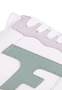 Zapatilla blanca con un logo de cuero verde, gamuza gris texturizada en la parte superior y cordones blancos. Presenta detalles cosidos a lo largo de las costuras.