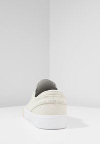 Baskets en daim crème avec une semelle en caoutchouc blanche, présentant une finition lisse, un bout arrondi et des accents à double texture sur le talon.