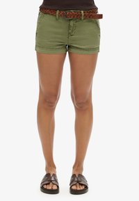 Shorts en coton vert olive avec poches avant et une ceinture en cuir tressé marron. Assortis à des sandales à glisser marron avec un design de bride.