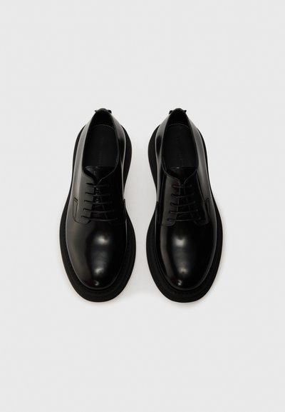 Black leather shoes with a smooth finish, lace-up design, rounded toe, and thick black sole. No visible patterns or hardware.