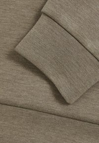Khaki sweatshirt stof, glat tekstur, foldet manschet synlig, som viser syningens detalje. Simpelt, praktisk design. Ingen mønstre eller accenter.