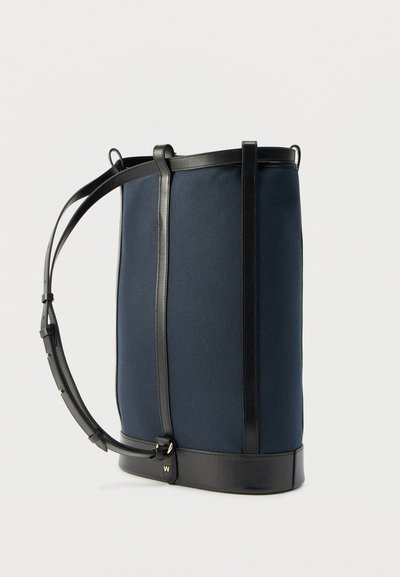 Σακίδιο πλάτης από καμβά σε ναυτικό μπλε με μαύρη δερμάτινη επένδυση, κατακόρυφες ραφές, ρυθμιζόμενους ιμάντες και μινιμαλιστικό σχεδιασμό. Διαθέτει δομημένο σχήμα.