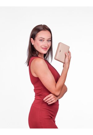 Beige wallet with a smooth texture and zip closure, held by a person wearing a fitted burgundy dress. Simple logo on the wallet front.