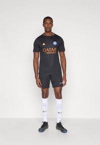 Μαύρη φανέλα ποδοσφαίρου με πορτοκαλί κείμενο "Qatar Airways", μπλε λογότυπο, συνδυασμένη με μαύρα σορτς. Λευκές κάλτσες και μαύρα παπούτσια ποδοσφαίρου με μπλε λεπτομέρειες.