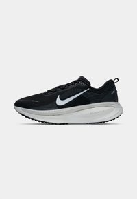 Tenisi sport negri cu un superior din plasă, logo alb, detalii texturate și un outsole masiv cu branding "zoomx". Talpa exterioară este de culoare neagră.