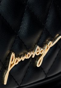Borsa nera in pelle trapuntata con un logo in oro prominente. La superficie presenta una finitura testurizzata con un motivo a diamante.