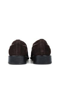 Brązowe zamszowe loafersy z gładką czarną gumową podeszwą i minimalnymi detalami przeszyć na cholewce. Projekt ma zaokrąglony nosek i styl loafersów.