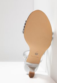 Sandale argentée à talons hauts avec semelle beige lisse, taille 37, avec un talon bas et large et une bride décorative à la cheville.
