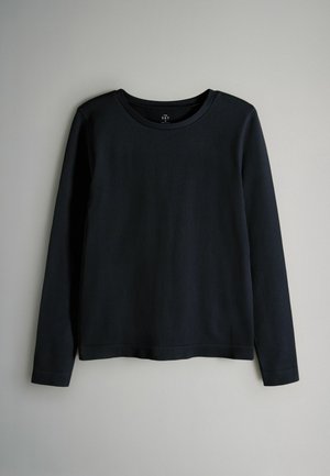 Svart långärmad ribbad topp med rund halsringning och avslappnad passform. Tyget verkar mjukt med en subtil textur. Inga synliga spännen eller mönster.