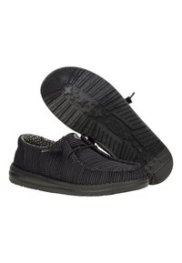 Schwarze Freizeit-Schuhe mit einem strukturierten Strick-Obermaterial, das eine flexible Gummisohle mit einem Sternmuster-Profil aufweist. Akzente sind die schwarze Ferse und die Schnürsenkel.