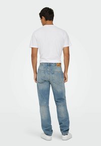Lysblå denimjeans med en afslappet pasform, der har et bæltetag, to baglommer og let falmning for tekstur. Båret med en hvid t-shirt.