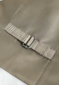 Tissu beige à motif avec un design en losanges texturé, doté d'une sangle rayée beige et d'une boucle en métal pour un maintien sécurisé.