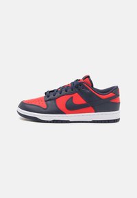 Sneaker navy e rossa con tomaia in pelle, punta perforata, suola intermedia bianca e suola esterna in gomma. Presenta il classico logo Nike sul lato.