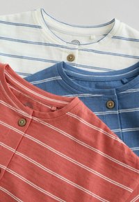 Tri zložené pruhované henley tričká v bielej, modrej a koralovej farbe, každé s okrúhlym výstrihom a jedným viditeľným gombíkom na golieri.