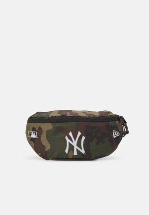 Riñonera de camuflaje con cierre de cremallera. Presenta un logo de los New York Yankees en blanco y un logo de la MLB en el lateral. Tejido duradero.