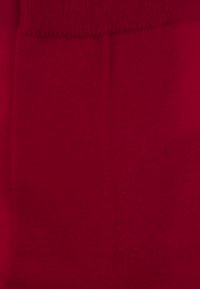 Red cotton fabric with a smooth texture and a ribbed waistband, showing even color distribution and no visible patterns or hardware.
