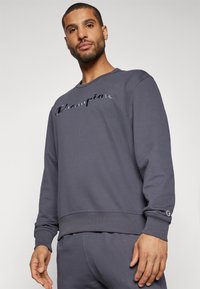 Dunkelgrauer Sweatshirt mit gerippten Bündchen und Saum. Enthält ein geprägtes "Champion"-Logo auf der Brust. Weicher Stoff mit lockerer Passform.