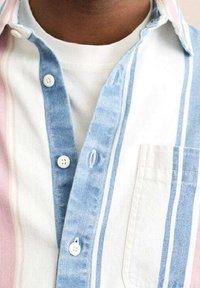 Koszulka z długim rękawem w paski, w kolorach niebieskim, różowym i białym. Posiada kieszeń na piersi i białe guziki. Miękka, teksturowana tkanina.