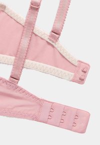Reggiseno rosa chiaro con spalline regolabili, texture morbida, dettagli in pizzo lungo i bordi e chiusura a gancio con tre regolazioni sulla banda.