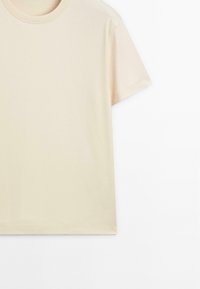 Beige katoenen T-shirt met ronde hals en korte mouwen. Soepele textuur, eenvoudig ontwerp, zonder zichtbare patronen of hardware.