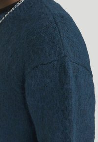 Dunkelblauer gestrickter Pullover mit strukturiertem Oberfläche, mit einem Rundhalsausschnitt und sichtbaren Nähten entlang der Schulternaht.